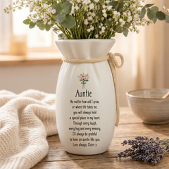A white vase with a bouquet of white flowers and greenery, along with a heartfelt message that reads "Auntie" and a poem about the love and care an aunt provides.