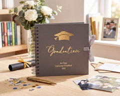 A graduation album with a graduation cap on top, surrounded by graduation-related items such as a graduation cap, a graduation gown, and confetti.