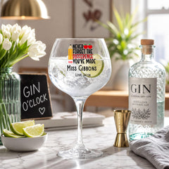 a table with a large gin glass, a bottle of gin, a bowl of lime wedges, and a blackboard sign.