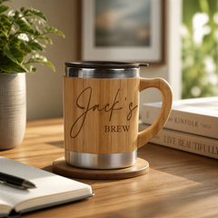 A wooden mug with the name "Jack's Brew" engraved on it, placed on a wooden coaster, with a notebook and a plant nearby.
