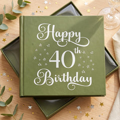 A green book titled "Happy 40th Birthday" with white text and star decorations on a wooden surface.