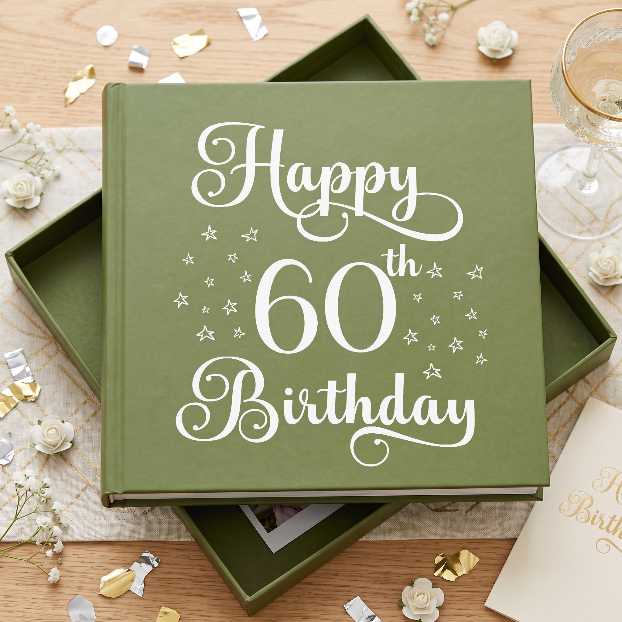 A green photo album with the text "Happy 60th Birthday" printed on it, surrounded by confetti and flowers on a wooden surface.