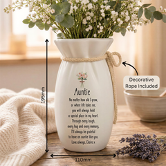 A white ceramic vase with a heartfelt message written on it, placed on a wooden surface.