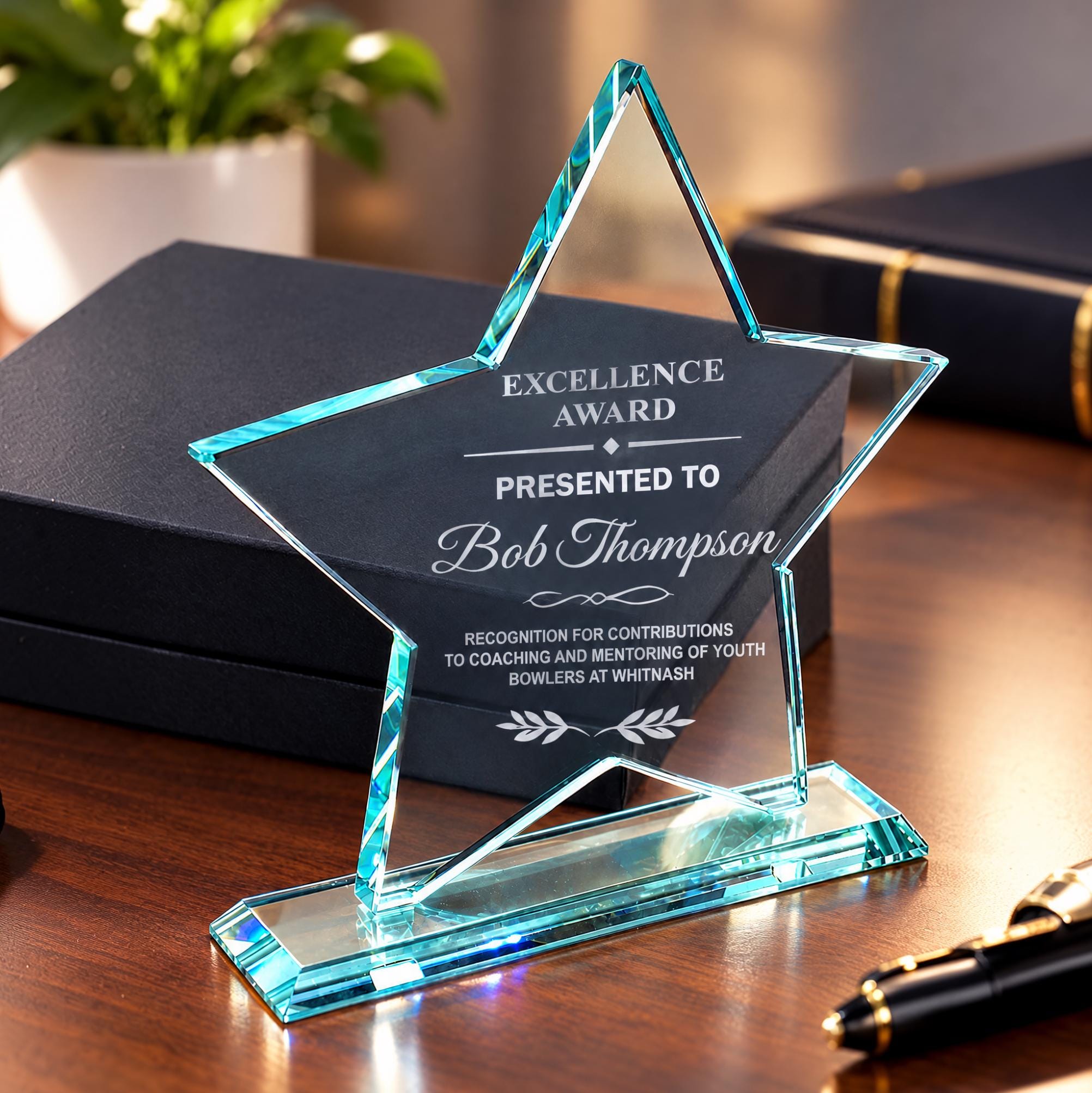 a star-shaped award on a wooden surface, with a black box and a pen nearby.