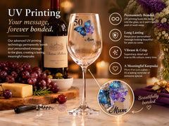 a wine glass with a butterfly design, a bottle of wine, and a wooden cutting board with grapes and cheese. The text highlights the UV printing technology that allows for permanent bonding of a message to the glass, creating a lasting keepsake.