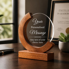 A wooden award or plaque with a clear glass front, featuring a personalized message and a wooden base.