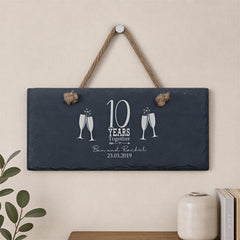 A slate sign with a rope and two champagne glasses, celebrating a 10-year anniversary.