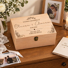 A wooden box on a wooden table, with a wedding photo frame and a book titled "Our Wedding" next to it.