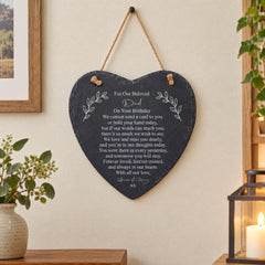 A heart-shaped slate hanging on a wall, with a heartfelt message written on it.