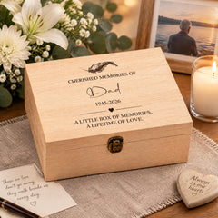 a wooden box with a personalized message, a candle, and some flowers on a table.