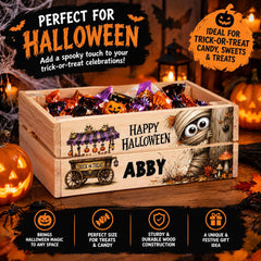 The image is an advertisement for a Halloween candy bin, featuring a wooden crate filled with Halloween-themed candy and a carved jack-o-lantern. The text on the advertisement highlights the bin's features, such as its perfect size, sturdy construction, and unique design, as well as its ideal use for trick-or-treat candy, sweets, and treats.