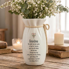 A white vase with a floral design and a heartfelt message, placed on a wooden surface.