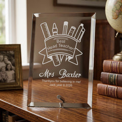 A glass picture frame with a personalized message engraved on it, placed on a wooden surface.