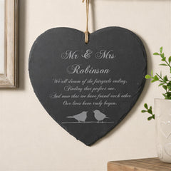 A heart-shaped slate hanging on a wall, with a message about Mr & Mrs Robinson and their love story.