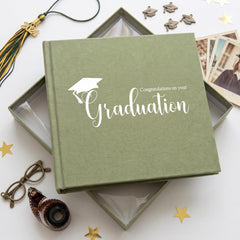 a graduation-themed photo album with a graduation cap and tassel, surrounded by graduation photos, a graduation cap, and a graduation gown.