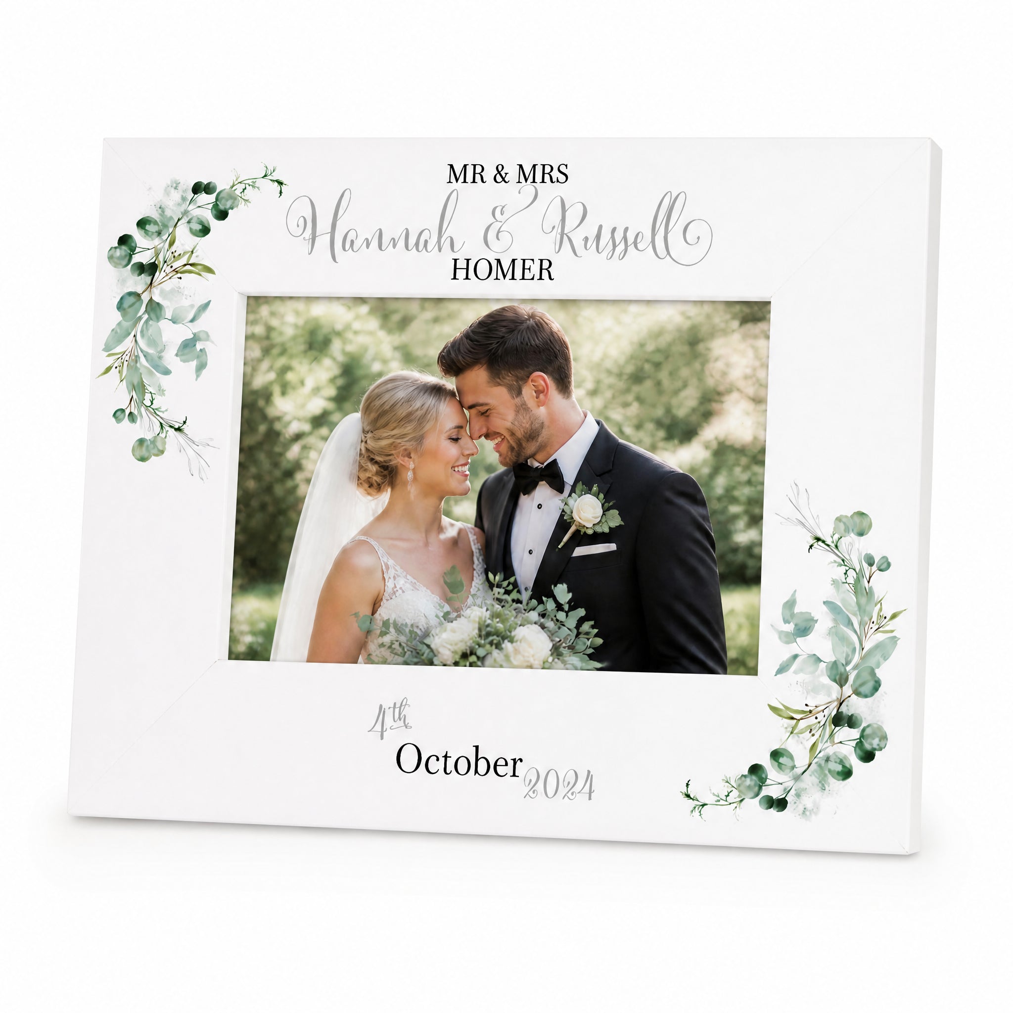 A white wedding picture frame with a bride and groom in the center, surrounded by a floral border. The frame has a personalized message that reads "Mr & Mrs Hannah & Russell HOMER" and the date "October 2034".