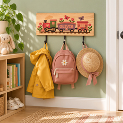 A wooden coat rack with a pink backpack, a straw hat, and a yellow raincoat hanging on it, set against a green wall.