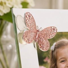 A close-up of a young girl's face with a pink butterfly-shaped frame holding a photo.