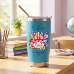 A blue tumbler with a colorful design and a straw, placed on a wooden desk in a room with books and a globe.